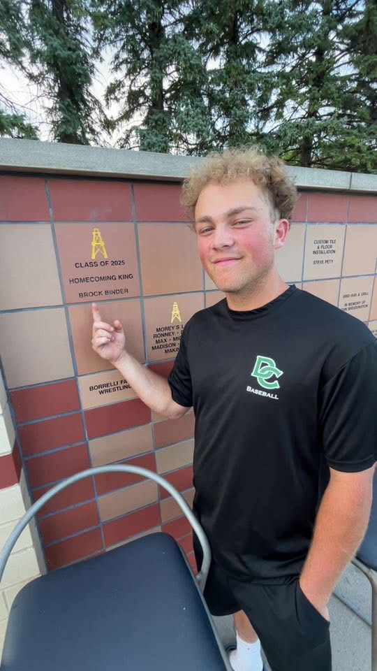 A 2025 graduate pointing out his engraved brick in the stadium donor wall