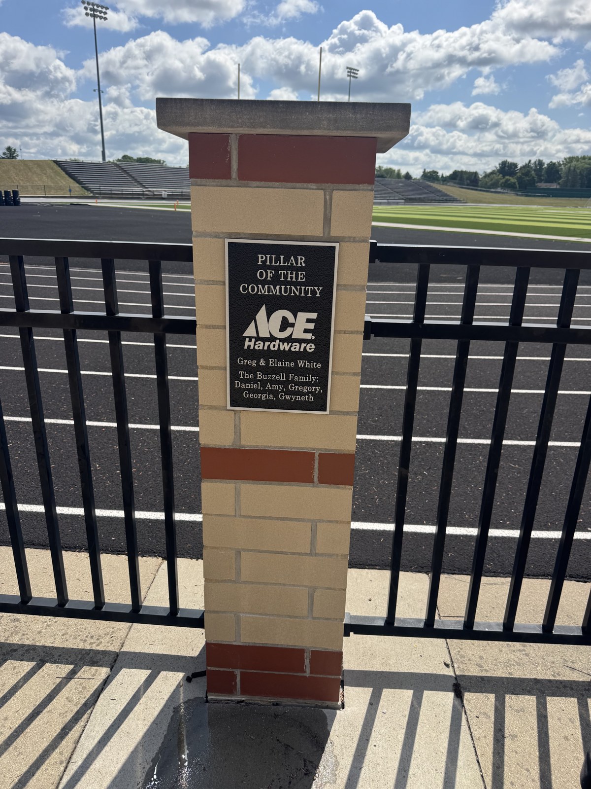 A Pillar of the Community plaque on a brick pillar beside the stadium track